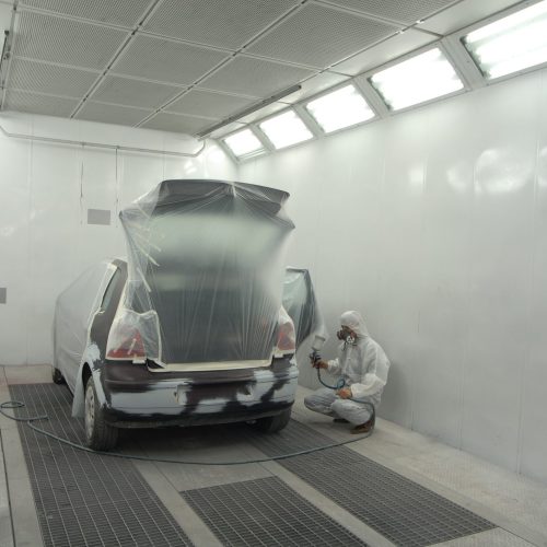 Man in white garage painting automobile